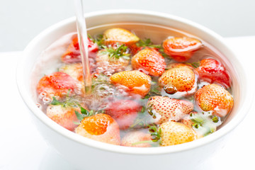 Strawberries soaked in water. Washing fresh fruit on white.