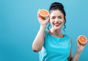 Happy young woman holding oranges on a blue background