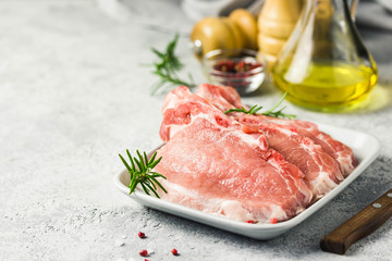 Raw pork chops, spices, herbs, olive oil. Selective focus, space for text.