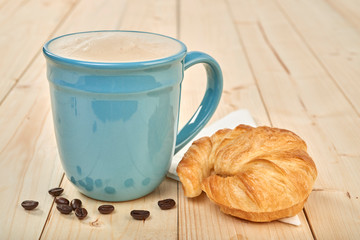 coffee with croissnt on a wooden table