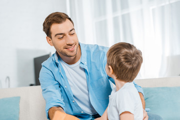 Fototapeta premium happy handsome father looking at preschooler son at home