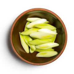 slices of green garlic in bowl isolated on white background