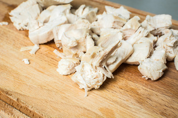 Sliced chicken breast for soup on wooden board.