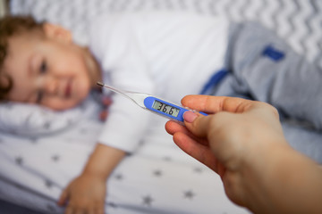 children's health. thermometer. in the background a healthy child is lying on the bed, the normal body temperature is