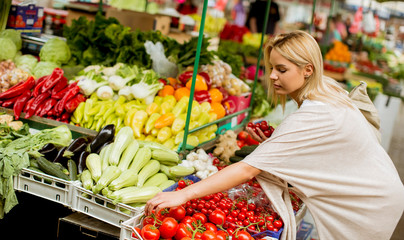 Cute young woman buying vegetables at the market