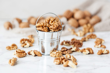 A bucket of walnuts on a marble table.