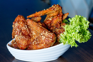 Yangnyean Chicken Wing coated with crushed nuts and lettuce on the side