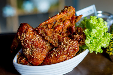 Yangnyean Chicken Wing coated with crushed nuts and lettuce on the side