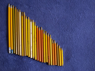 Color pencils on a purple plaid. Yellow pencils
