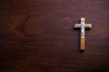 Funeral concept. Wooden cross on dark wooden background top view copy space