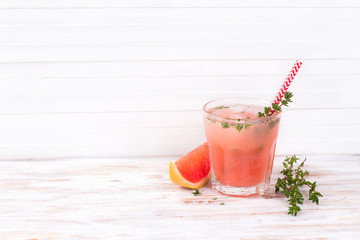 Healthy summer drink grapefruit lemonade with thyme in glasses with ice on a wooden surface
