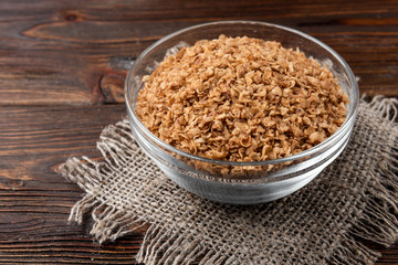 Buckwheat flakes on dark wooden background.
