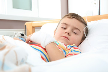 Little child with intravenous drip sleeping in hospital bed