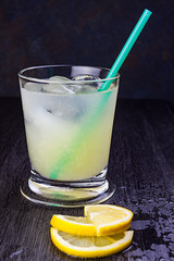 VASO DE ZUMO DE LIMÓN CON RODAJAS SOBRE FONDO DE MADERA OSCURA