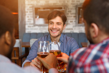 Friends drinking beer, celebrating meeting in bar