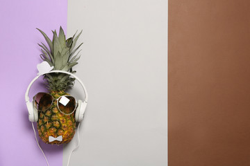 Funny pineapple with headphones and sunglasses on color background, top view. Space for text