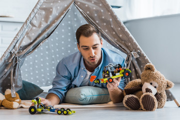 adult man lying in wigwam and playing with toys in nursery © LIGHTFIELD STUDIOS
