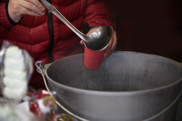 Fototapeta na wymiar Seller pouring hot mulled wine into cup, closeup