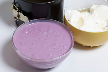 Blueberry cheesecake. Cottage cheese jelly with sour cream and blueberry jam. Ingredients for cooking are located on the surface of the table.
