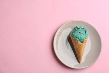 Plate with delicious spirulina ice cream cone on color background, top view. Space for text