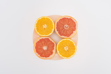 top view of sliced oranges and grapefruits on plate isolated on white