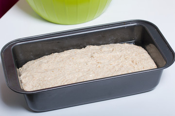 Baking bread at home. Wholemeal dough lies in bread pan.