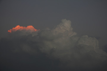 Edge of dark storm cloud is illuminated by ray of sunset sun. Hope concept