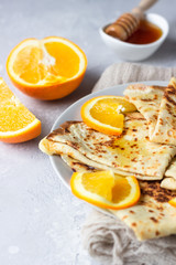 Crepes with orange, honey and natural yogurt or sour cream. Thin pancakes. Light concrete background. Copy space.