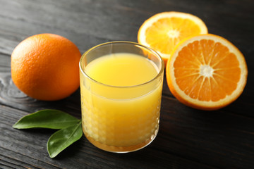 Glass with orange juice and fresh fruit on wooden background