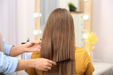 Fototapeta premium Professional coiffeuse combing client's hair in salon