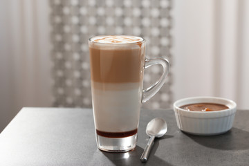 Glass cup of caramel macchiato and syrup on table