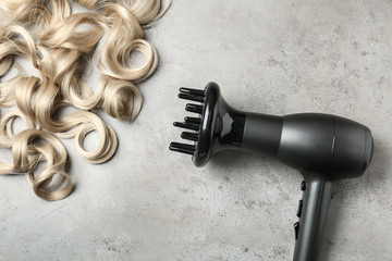 Obraz na płótnie Canvas Curly hair locks and dryer on grey background, top view