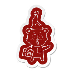 laughing teddy  bear with christmas present wearing santa hat