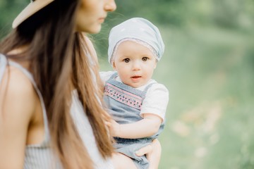 Happy and beautiful mom resting with her little daughter walking in the nature in the park in a sunny evening