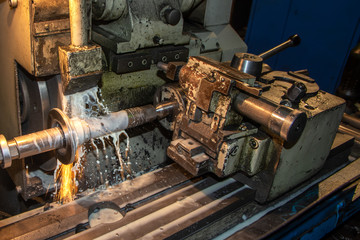 Closeup big industrial CNC lathe machine cutting the steel rod with sparks