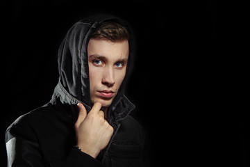 Portrait of a young man in the hood black background