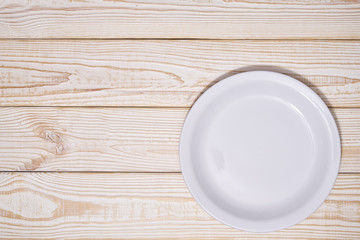 Empty white plate on a wooden background, top view.