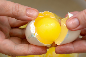 in female hands a broken egg with a yolk