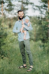 portrait of father and child. A stylish father with a beard keeps on his arms a child, a little girl, they embrace and smile, rejoice and have fun. Happy Father's Day