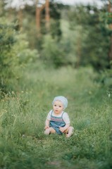 A smiling child is enjoying the nature sitting on the grass