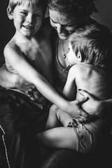 Mother holding two young sons in black and white.