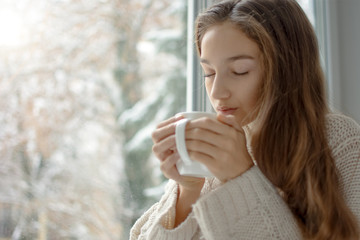 Woman drinking coffee in front of window