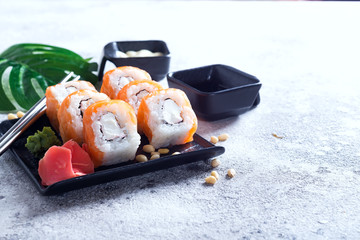 cream cheese Philadelphia roll classic on a stone black plate with chopsticks and sauce . Japanese sushi food. Copy space