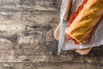 Spanish serrano ham sandwich on wooden table. Top view. Copyspace