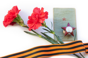 Two carnations, the Order of the Red Star, a military book and St. George ribbon on a white background. Isolated items.  9 may