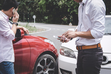 Two drivers man arguing after a car traffic accident collision and making phone call to Insurance Agent, Traffic Accident and insurance concept