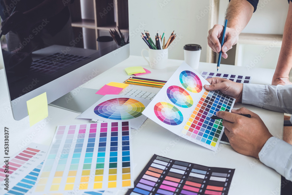 Poster Two colleagues creative graphic designer working on color selection and drawing on graphics tablet at workplace