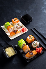 Traditional Japanese food- sushi, rolls, chopsticks, soy sauce on black slate background. Sushi menu. Top view copy space