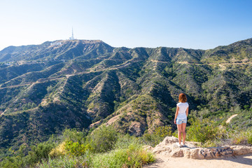 Young woman looking at the Hollywood sign in Los Angeles, California, USA. Dreaming about going to...