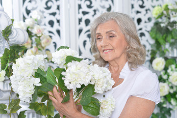 Portrait of happy senior woman posing with flowers 